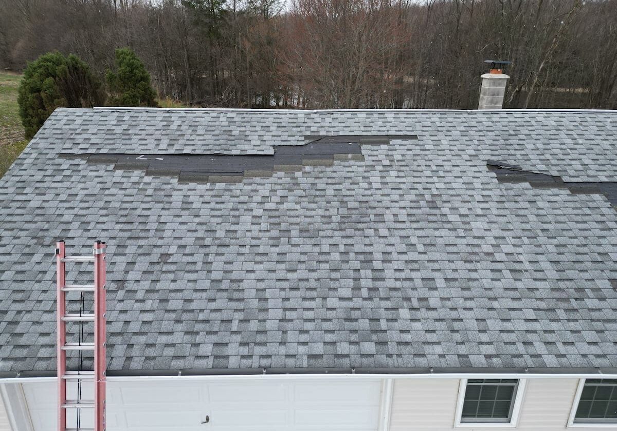 Storm damaged asphalt shingle roof with missing shingles and visible wind damage in Northeastern Pennsylvania